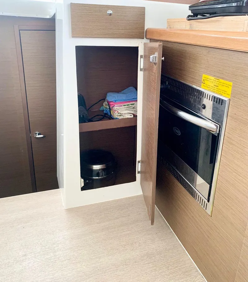 Slide: The Image of 2019 Lagoon 380 S2 yacht interior with wooden cabinetry and built-in oven. - 21