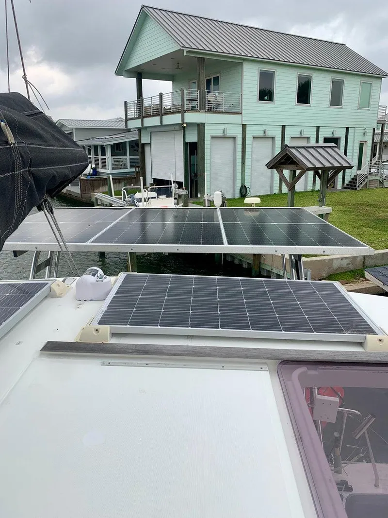 Slide: The Image of 2019 Lagoon 380 S2 4/2 catamaran with solar panels, docked near a modern house. - 6