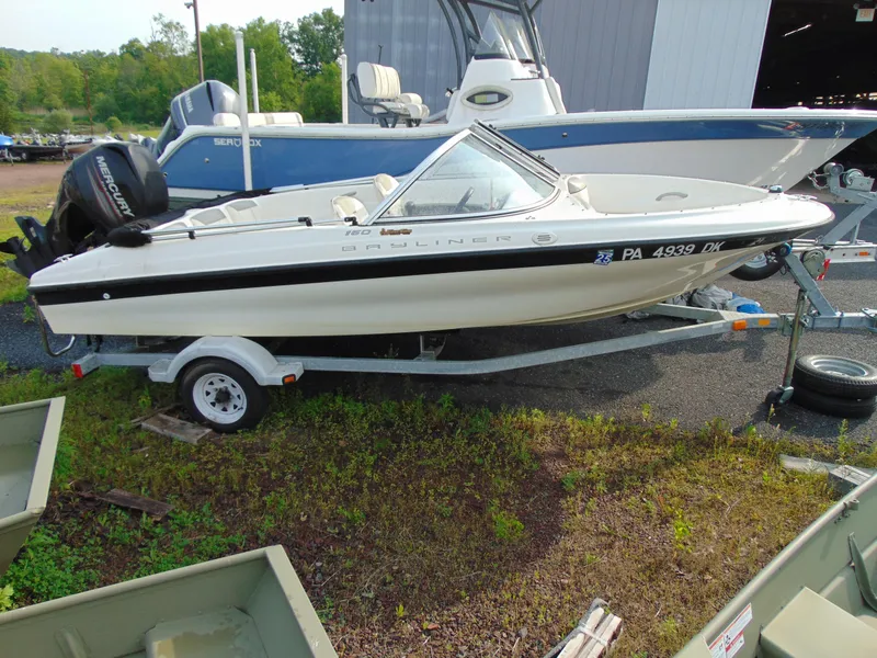 Slide: The Image of 2013 Bayliner 160BR boat on trailer, parked outdoors near other boats. - 1