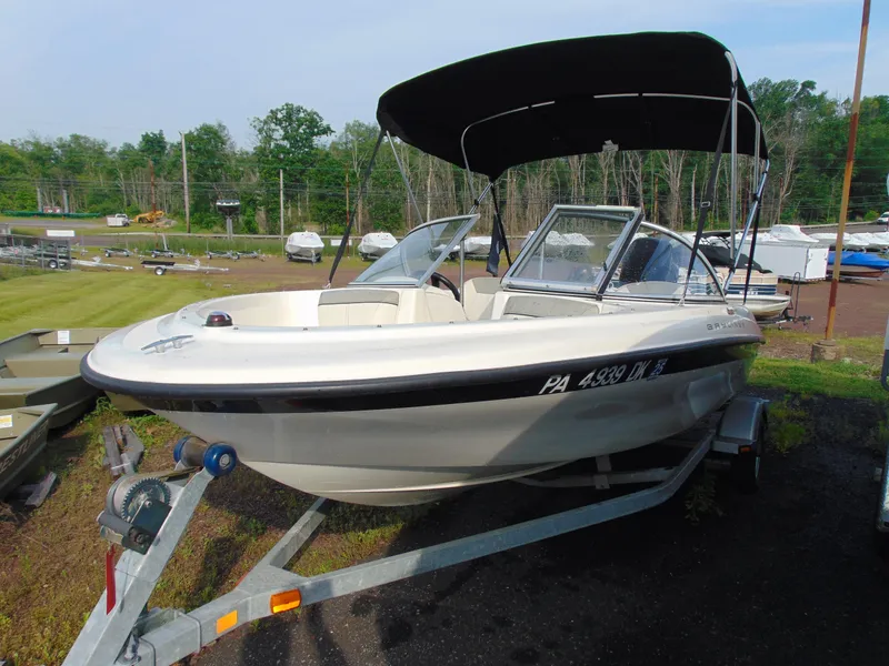 Slide: The Image of 2013 Bayliner 160BR boat on trailer with canopy, parked outdoors. - 3