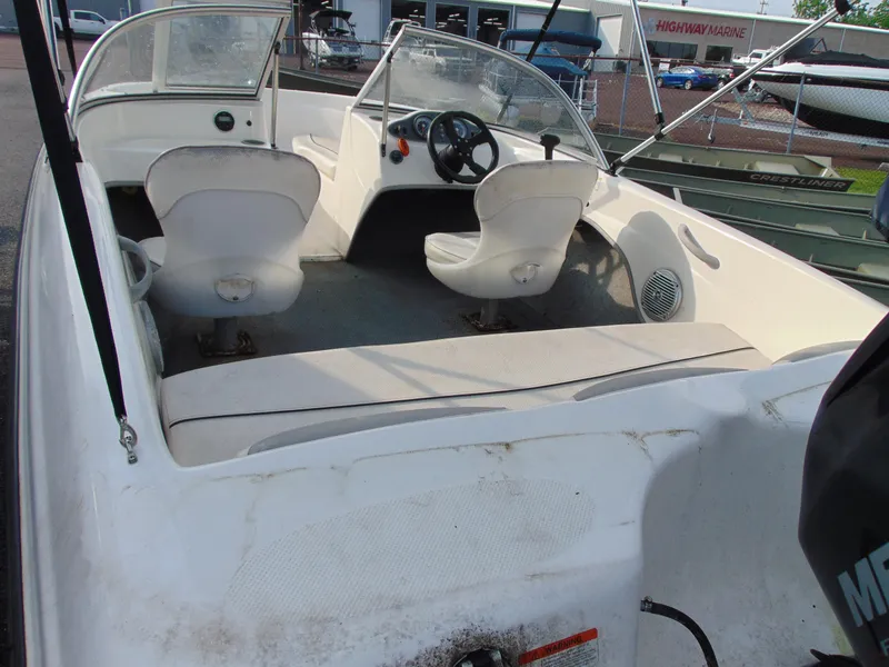 Slide: The Image of 2013 Bayliner 160BR boat interior with white seating and steering wheel. - 7