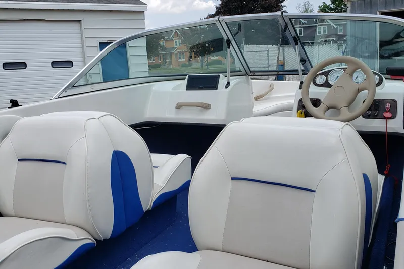 Slide: The Image of Interior of a 1998 Sunbird 150 boat with white and blue seating. - 3