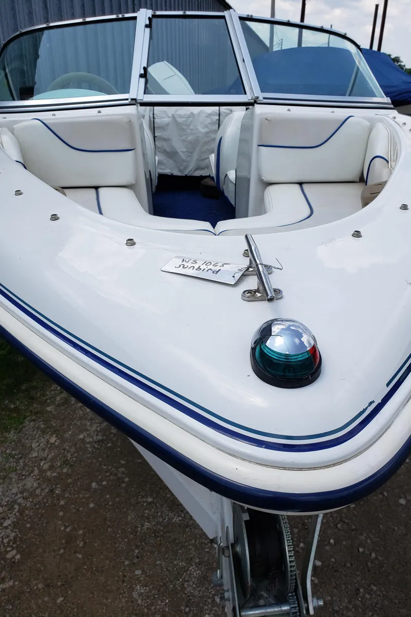 Slide: The Image of 1998 Sunbird 150 boat with white and blue interior, docked on a trailer. - 4