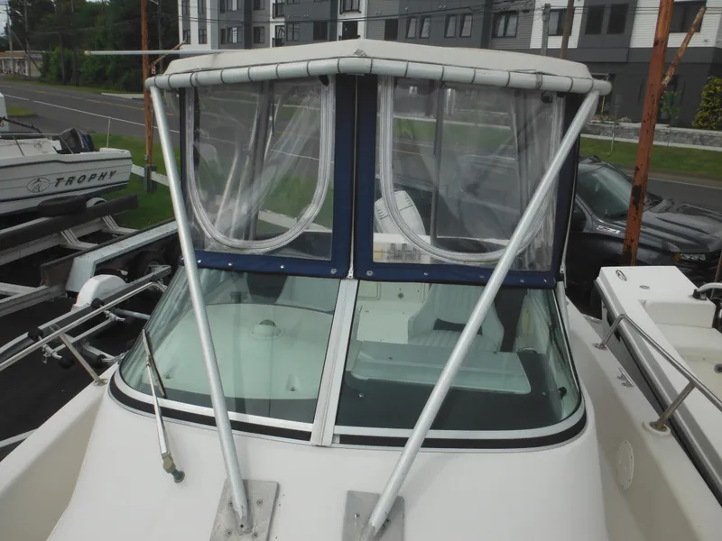 Slide: The Image of 1997 Pro-Line 231 WA boat with windshield and canopy, docked near other vessels. - 44