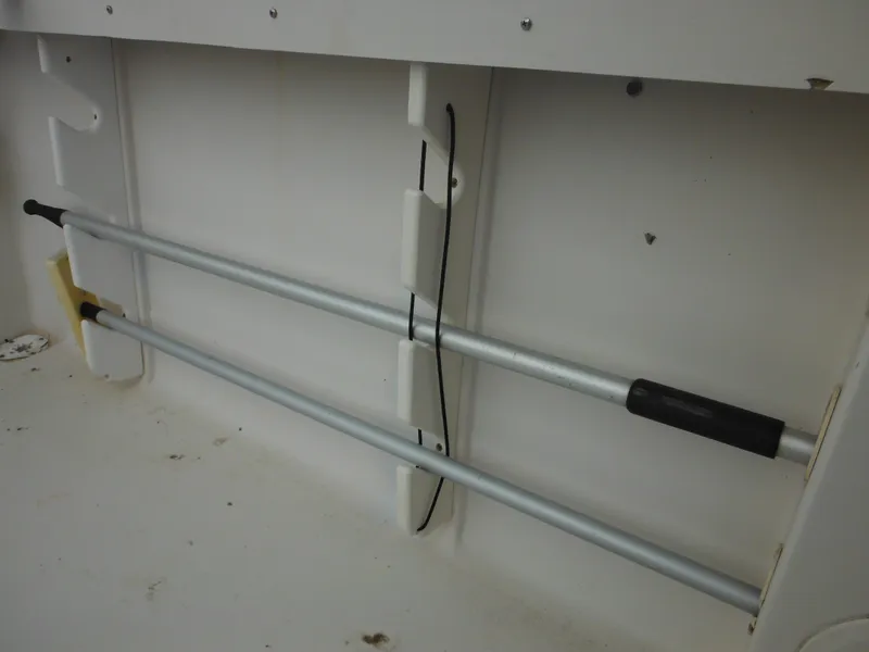 Slide: The Image of Storage compartment in a 1997 Pro-Line 231 WA boat, featuring mounted rods. - 47