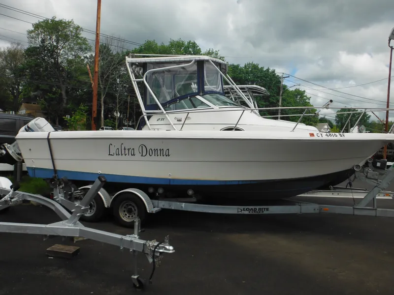 Slide: The Image of 1997 Pro-Line 231 WA boat on trailer, named "L'altra Donna," parked outdoors. - 5