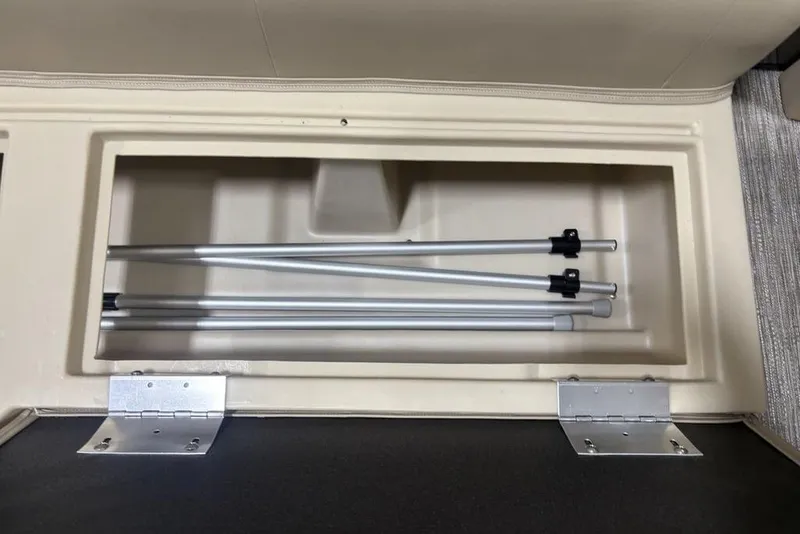 Slide: The Image of Storage compartment in 2025 Godfrey Xperience 2286 SBX boat, featuring aluminum poles. - 12