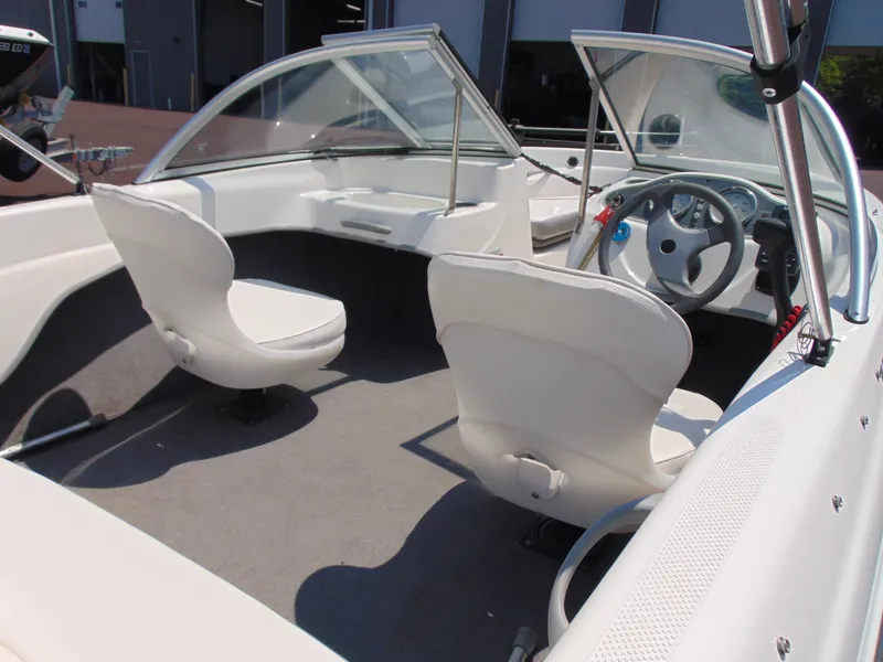 Slide: The Image of 2010 Bayliner 160 Bowrider interior with white seating and steering wheel. - 9
