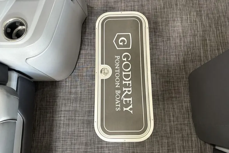 Slide: The Image of Floor hatch on 2025 Godfrey Sweetwater 2286 SFL pontoon boat, featuring logo and textured flooring. - 15