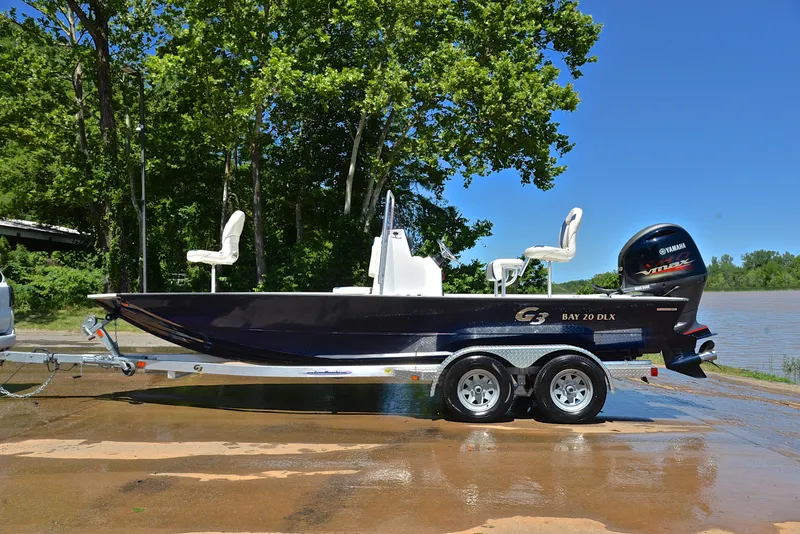 Slide: The Image of 2019 G3 Bay 20 DLX boat on trailer by a lake, surrounded by trees. - 11