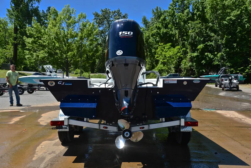 Slide: The Image of 2019 G3 Bay 20 DLX boat with 150 HP engine on trailer, surrounded by trees. - 13