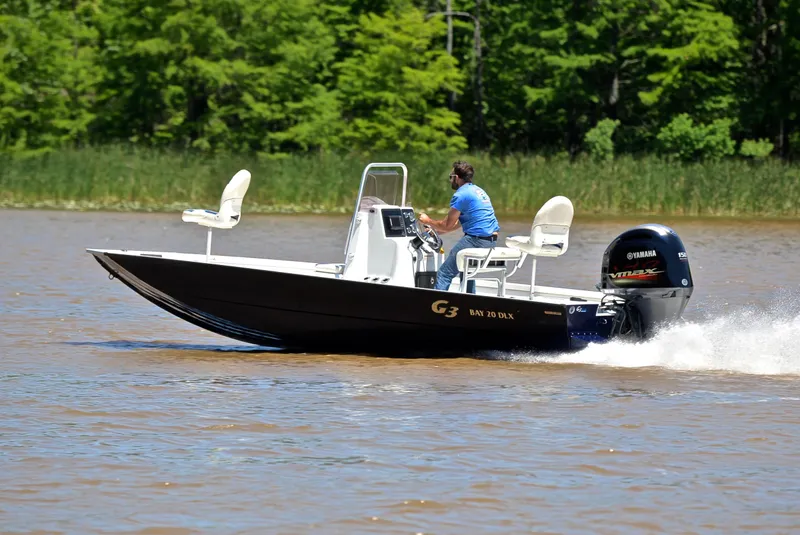 Slide: The Image of 2019 G3 Bay 20 DLX boat cruising on a lake with lush green background. - 4