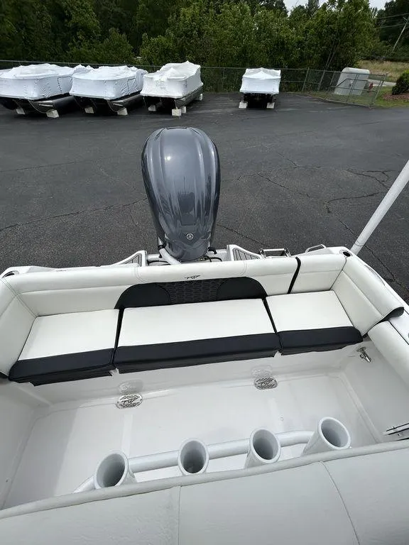 Slide: The Image of 2025 Tidewater 232 LXF boat with cushioned seating and outboard motor in a parking area. - 11