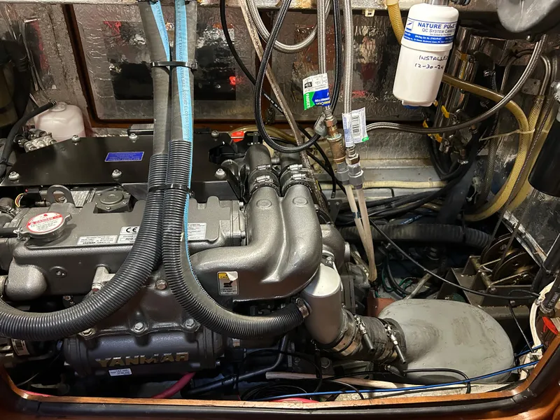 Slide: The Image of Engine compartment of a 2004 Passport 470 boat, featuring Yanmar components and various hoses. - 14