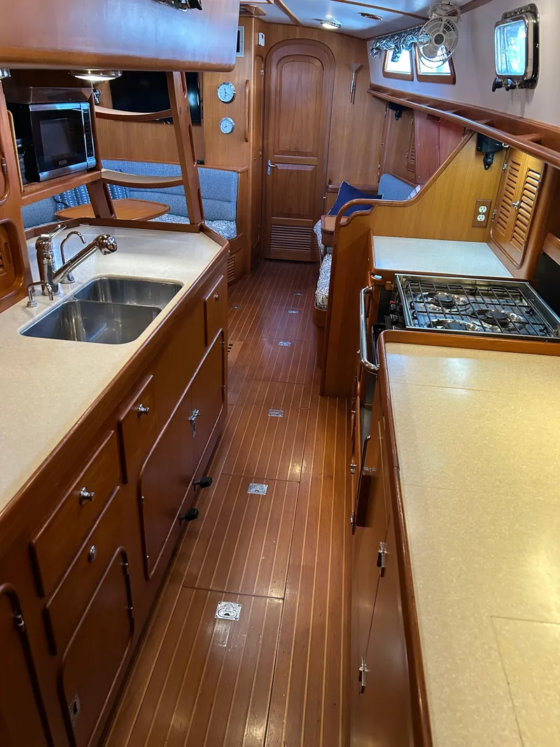 Slide: The Image of 2004 Passport 470 yacht interior with wooden cabinetry, kitchen sink, and stove. - 20