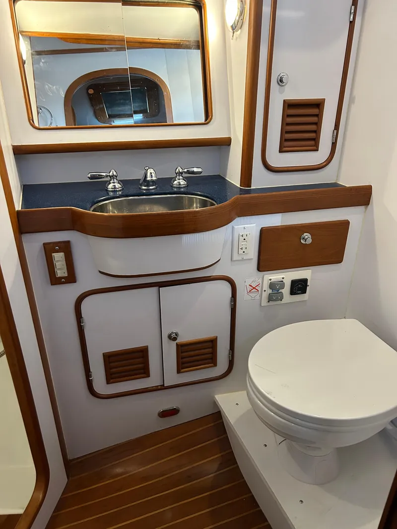 Slide: The Image of Compact bathroom in a 2004 Passport 470 yacht, featuring a sink, mirror, and toilet. - 21