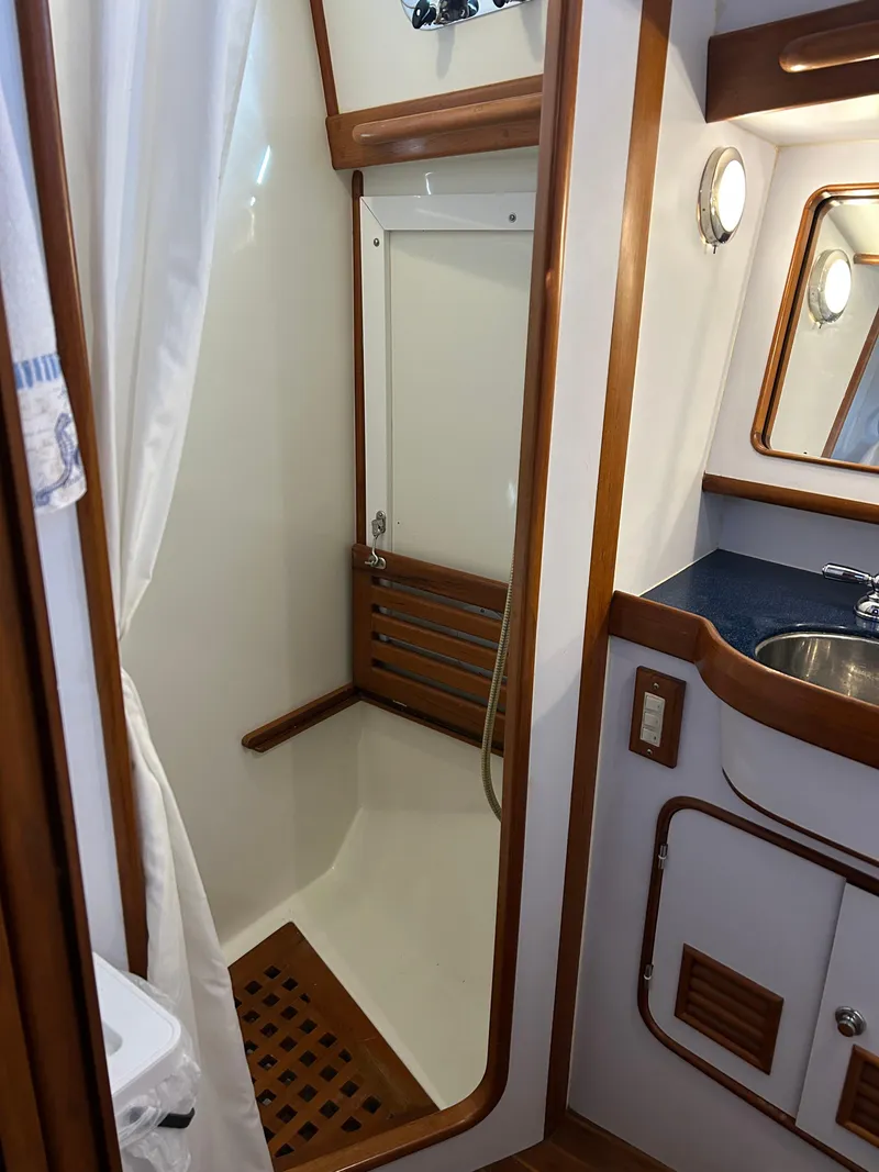 Slide: The Image of 2004 Passport 470 yacht bathroom with shower, wooden accents, and sink. - 22