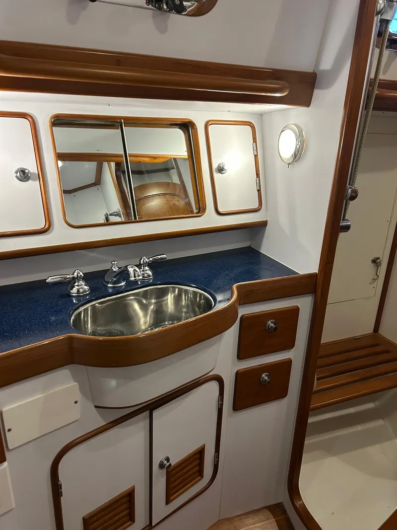 Slide: The Image of 2004 Passport 470 yacht bathroom with sink, mirror, and wooden accents. - 23
