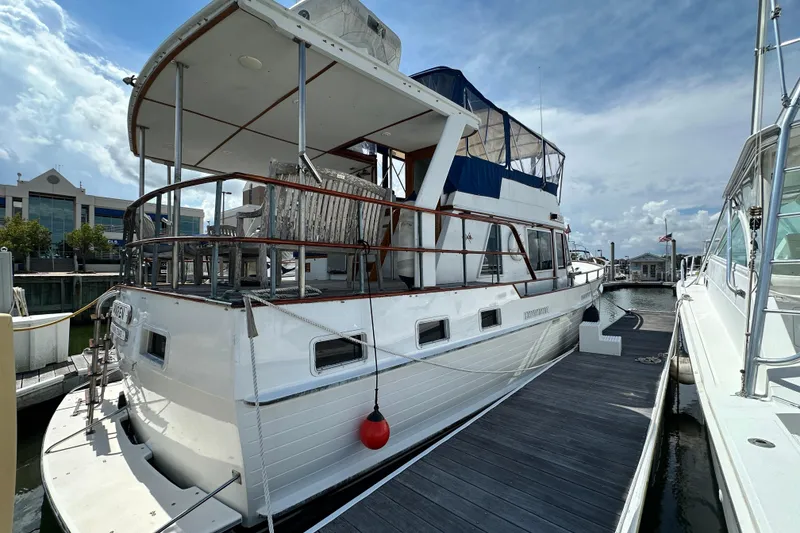 Slide: The Image of 1980 Island Gypsy Flush Aft Deck Trawler-Motor Yacht docked at marina under cloudy sky. - 1