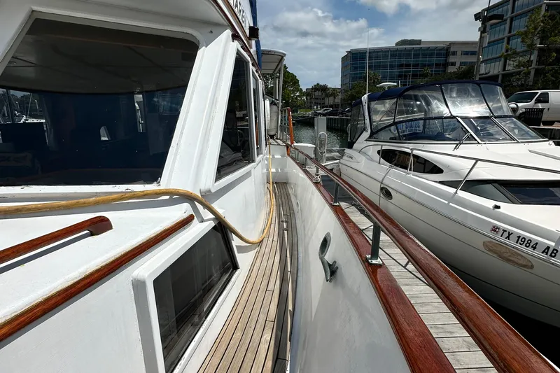 Slide: The Image of 1980 Island Gypsy Flush Aft Deck Trawler-Motor Yacht docked beside another boat. - 12