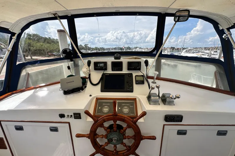 Slide: The Image of 1980 Island Gypsy Flush Aft Deck Trawler-Motor Yacht helm with navigation equipment and wooden wheel. - 21