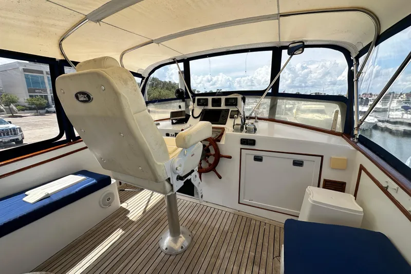 Slide: The Image of 1980 Island Gypsy Flush Aft Deck Trawler-Motor Yacht helm with wooden wheel and seating. - 26