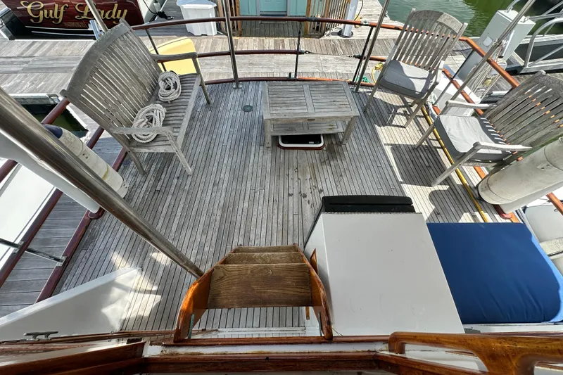 Slide: The Image of 1980 Island Gypsy Flush Aft Deck Trawler-Motor Yacht with wooden seating and table on deck. - 28