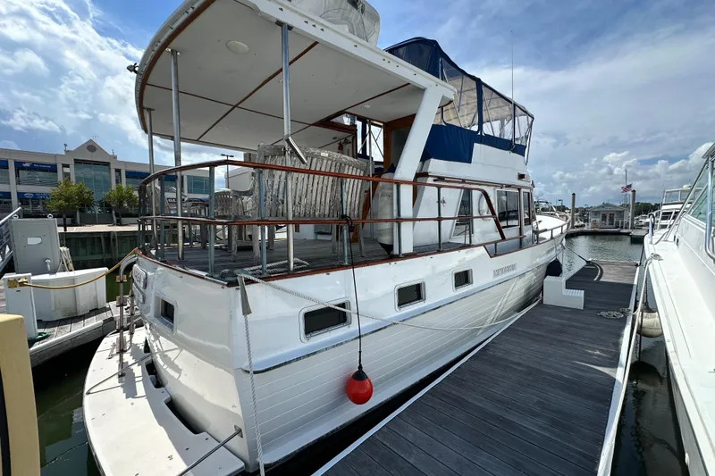 Slide: The Image of 1980 Island Gypsy Flush Aft Deck Trawler-Motor Yacht docked at marina under cloudy sky. - 3