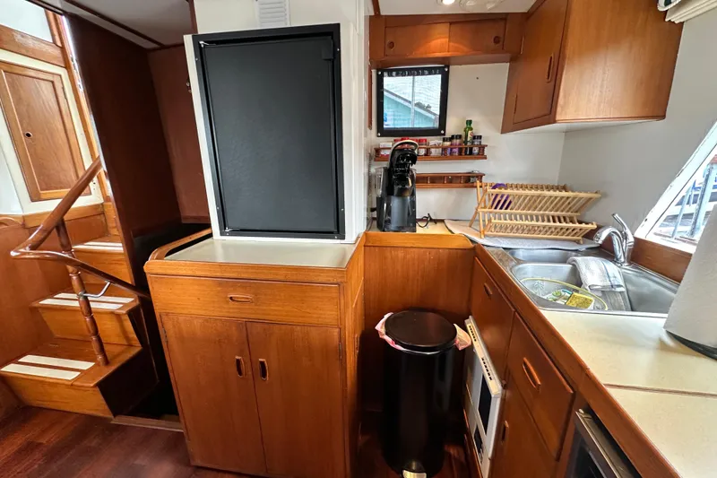 Slide: The Image of 1980 Island Gypsy yacht kitchen with wooden cabinetry, stairs, and modern appliances. - 43