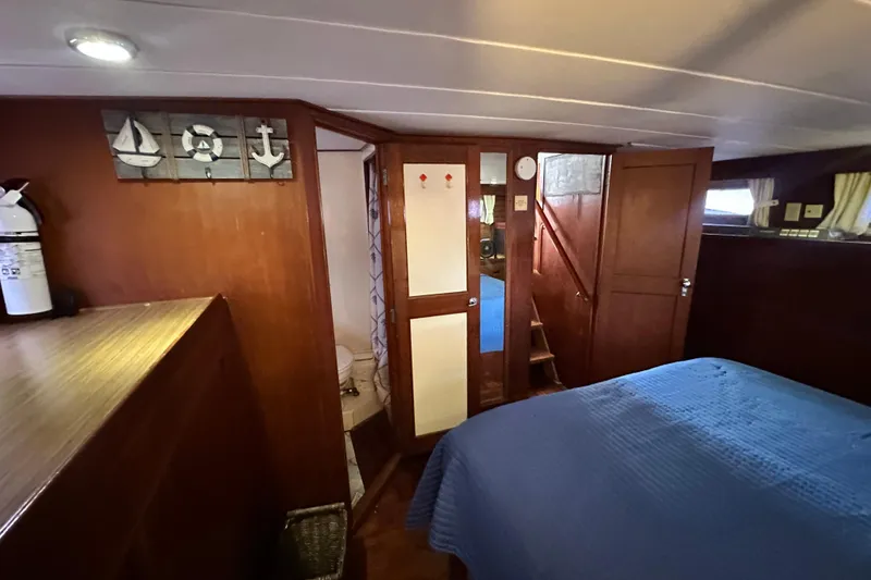 Slide: The Image of 1980 Island Gypsy Flush Aft Deck Trawler-Motor Yacht interior with wood paneling and blue bedding. - 47
