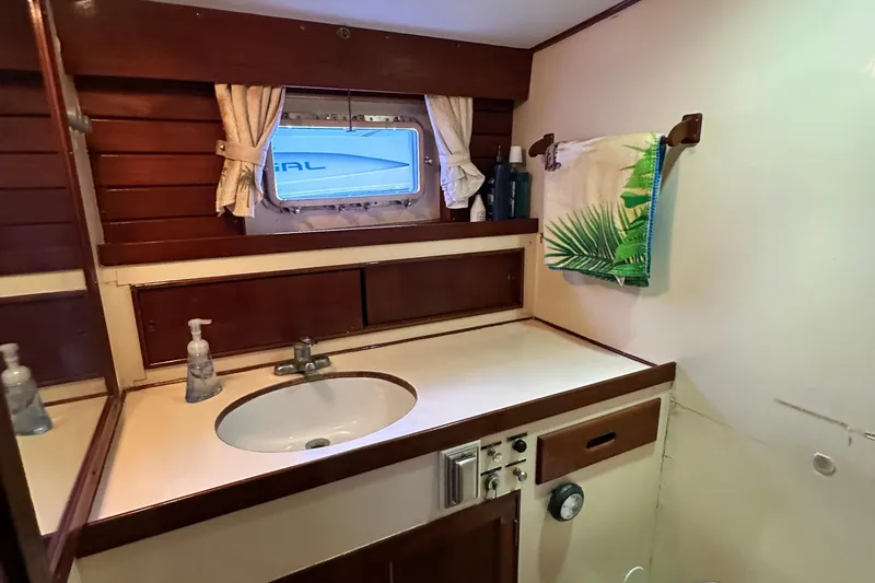 Slide: The Image of 1980 Island Gypsy yacht bathroom with wooden accents, sink, and tropical-themed towel. - 49