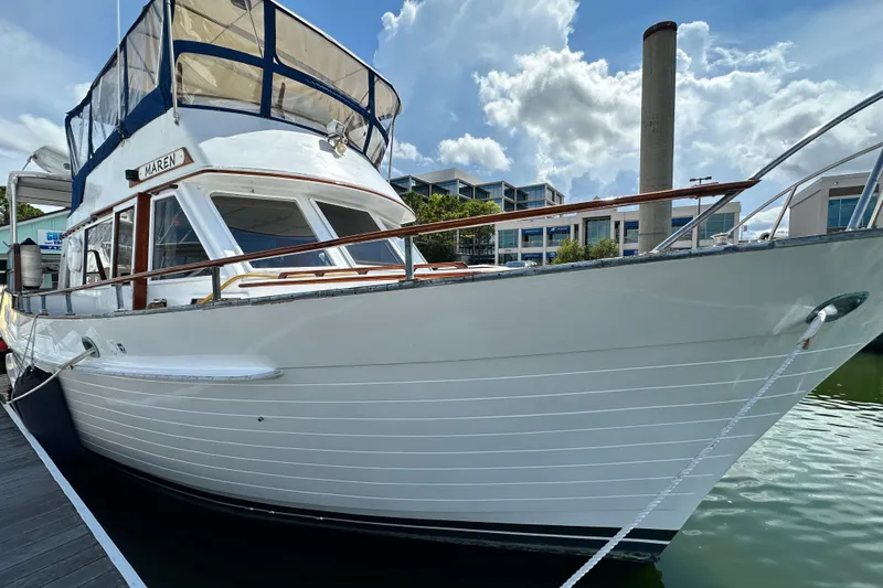 Slide: The Image of 1980 Island Gypsy Flush Aft Deck Trawler-Motor Yacht docked under a cloudy sky. - 5
