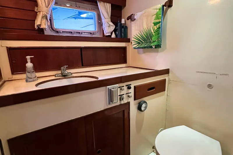 Slide: The Image of 1980 Island Gypsy yacht bathroom with sink, porthole, and tropical-themed towel. - 51