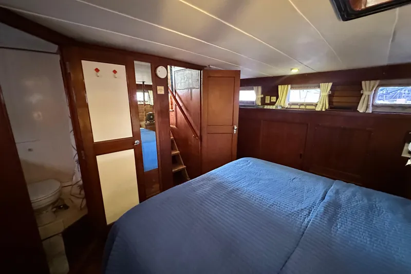 Slide: The Image of 1980 Island Gypsy yacht cabin with wood paneling, blue bedding, and small windows. - 54