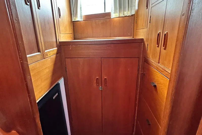 Slide: The Image of 1980 Island Gypsy yacht interior with wooden cabinets and drawers, featuring natural light. - 58