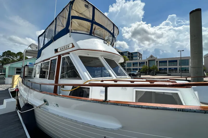 Slide: The Image of 1980 Island Gypsy Flush Aft Deck Trawler-Motor Yacht docked under a partly cloudy sky. - 6
