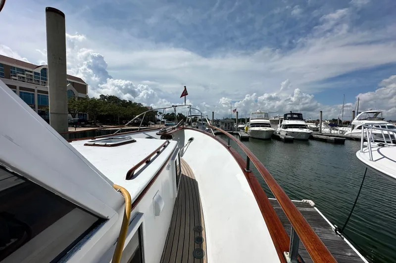 Slide: The Image of 1980 Island Gypsy Flush Aft Deck Trawler-Motor Yacht docked at marina under cloudy sky. - 8