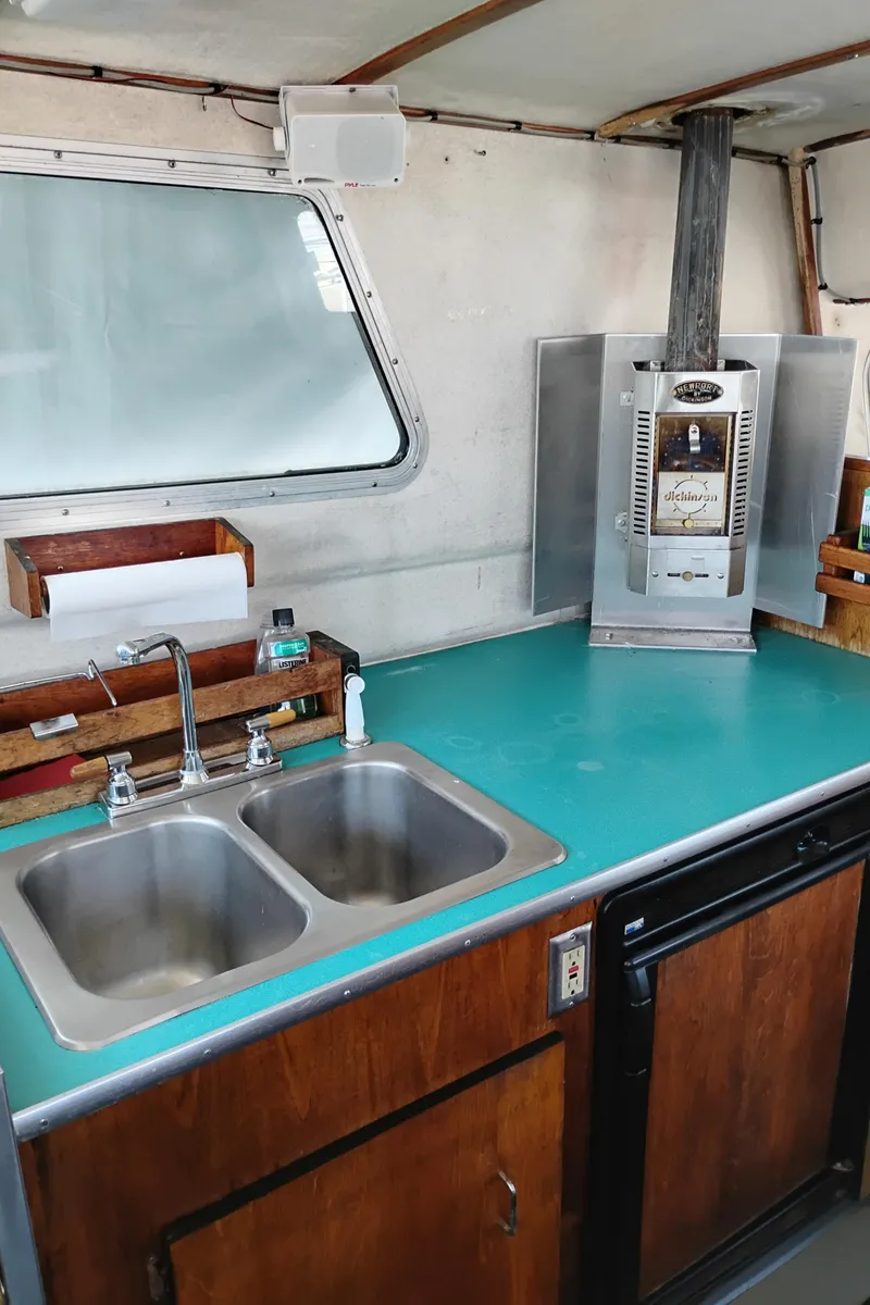 Slide: The Image of 1996 Martin Trunk Cabin kitchen with teal countertop, dual sink, and compact stove. - 17