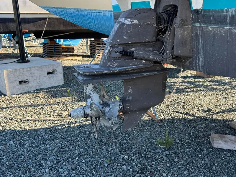 Slide: The Image of Aged boat propeller on a 1996 Martin Trunk Cabin, resting on gravel. - 34