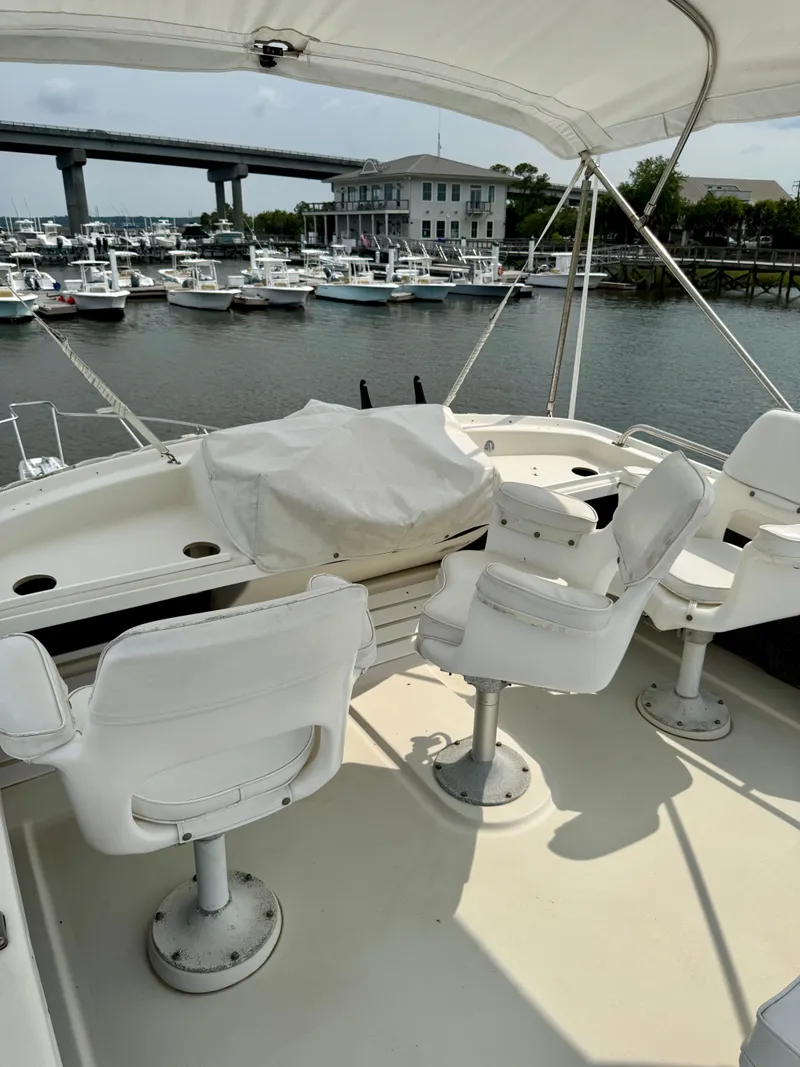 Slide: The Image of 1986 Silverton 34 Convertible Flybridge with marina view, featuring white seating and covered controls. - 11