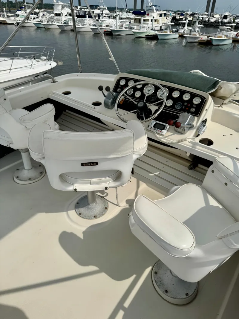 Slide: The Image of 1986 Silverton 34 Convertible Flybridge with white seating and control panel, docked at marina. - 14