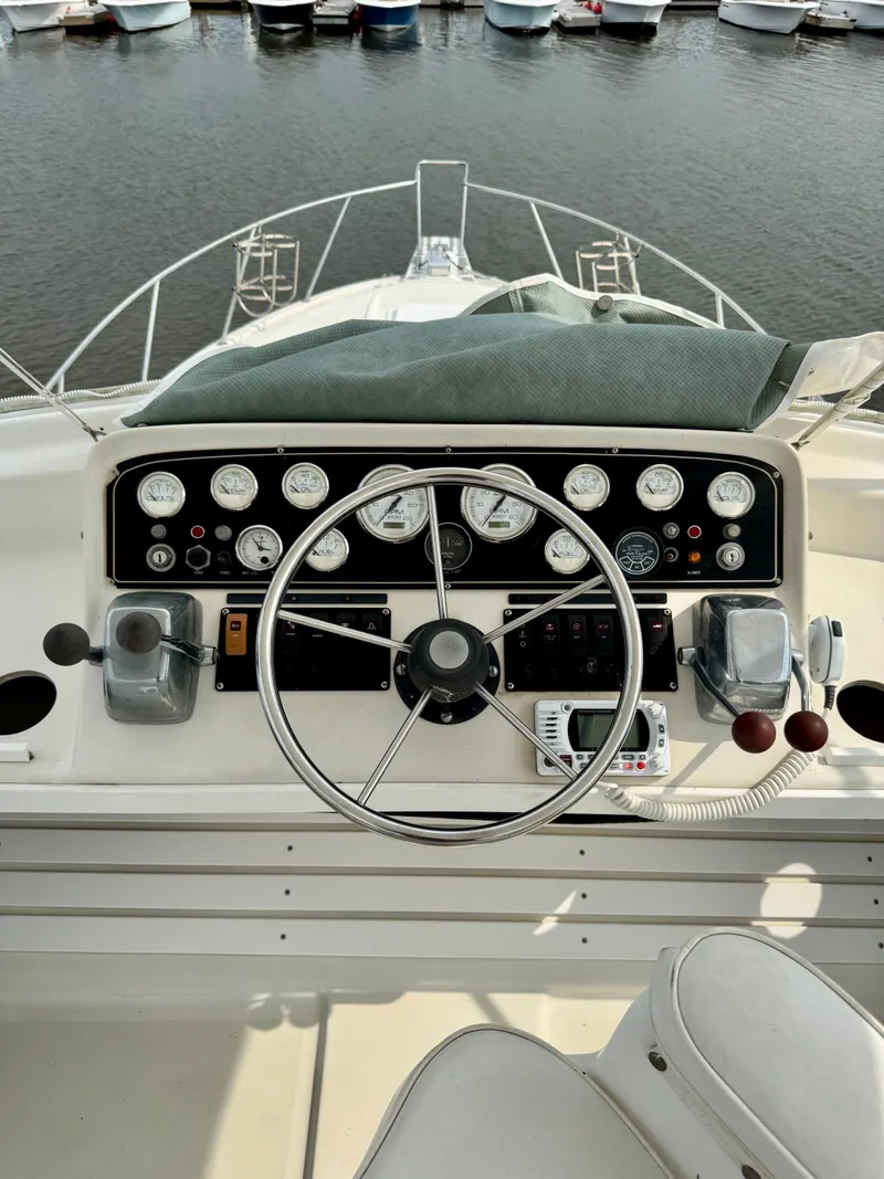 Slide: The Image of 1986 Silverton 34 Convertible Flybridge helm with gauges and steering wheel, docked at marina. - 15