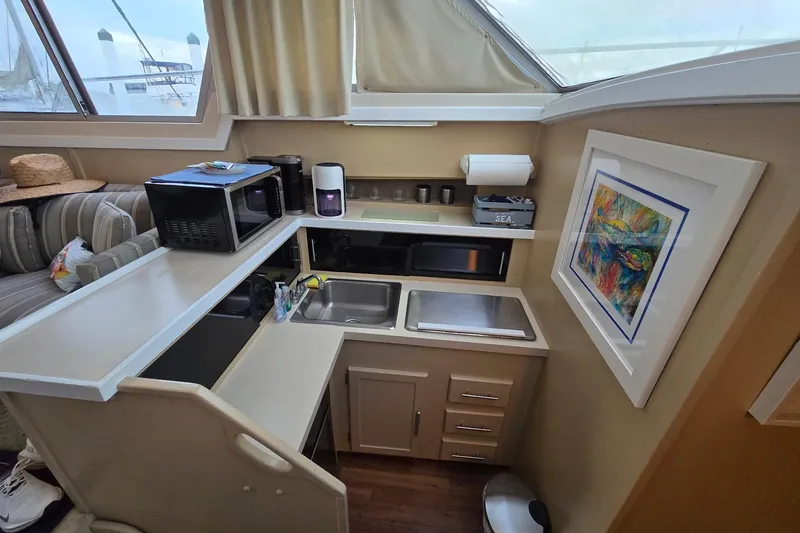 Slide: The Image of 1986 Silverton 34 Convertible Flybridge interior kitchen with microwave, sink, and colorful artwork. - 21