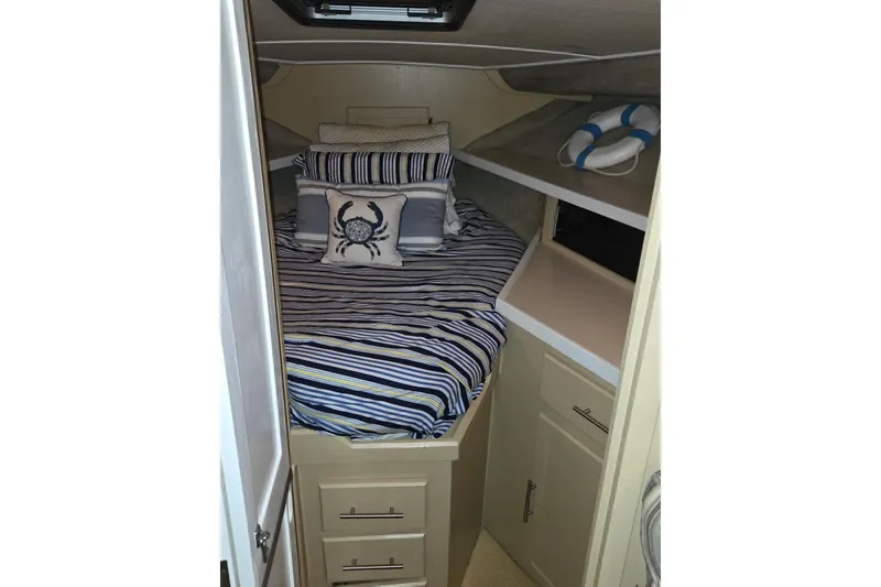 Slide: The Image of 1986 Silverton 34 Convertible Flybridge cabin with striped bedding and nautical decor. - 27