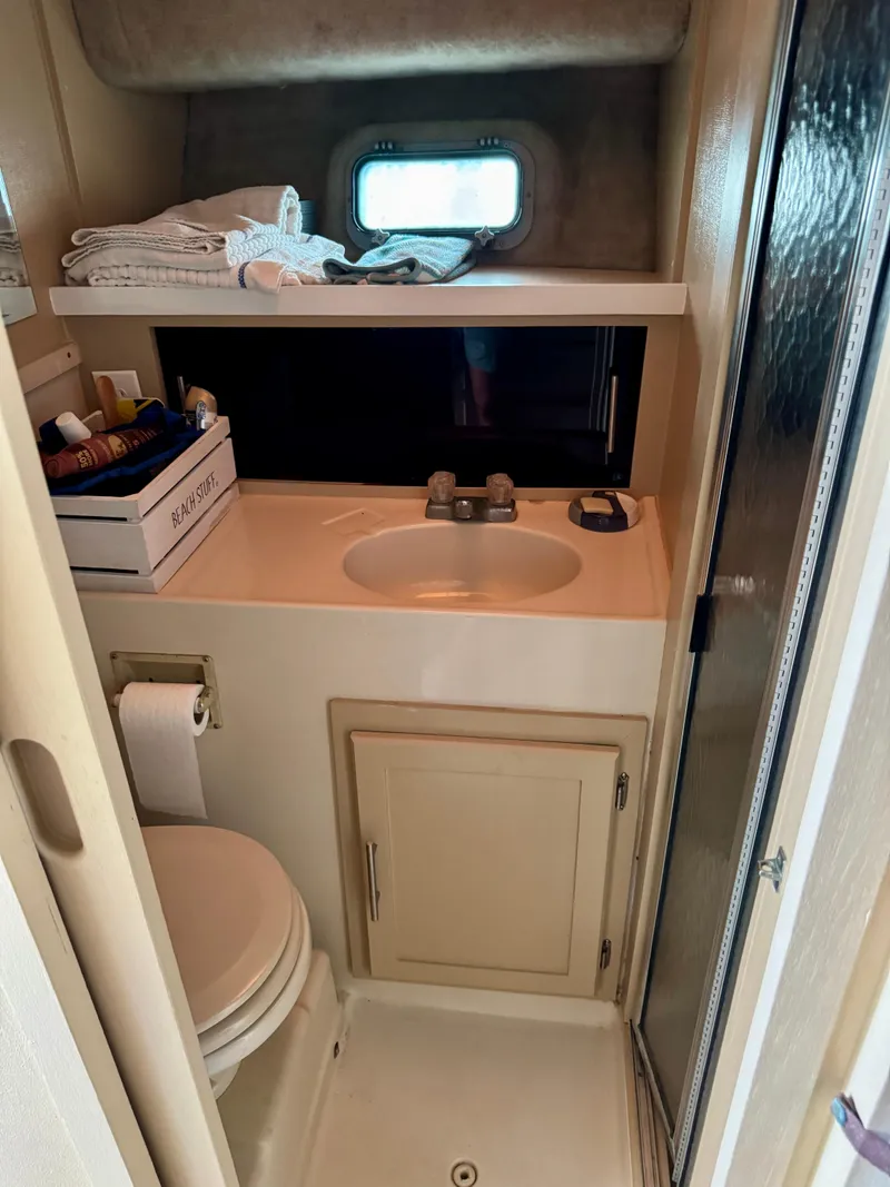 Slide: The Image of 1986 Silverton 34 Convertible Flybridge bathroom with sink, toilet, and storage cabinet. - 29