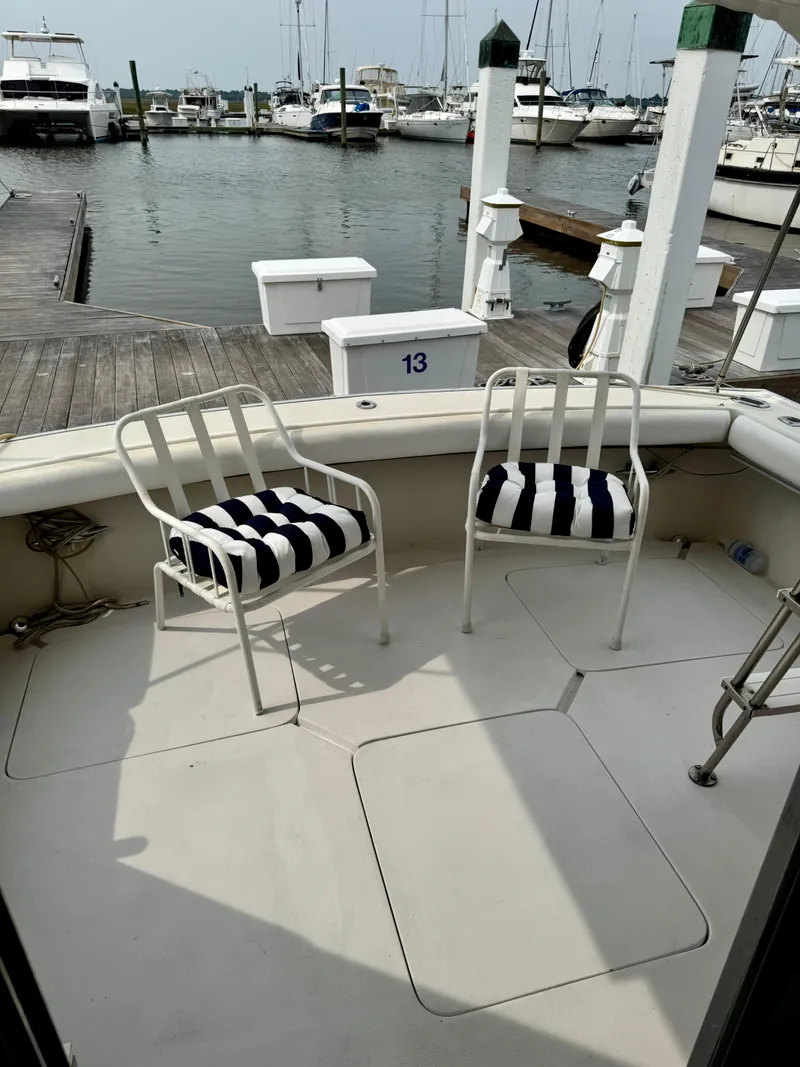 Slide: The Image of 1986 Silverton 34 Convertible Flybridge with striped chairs on deck at marina. - 6