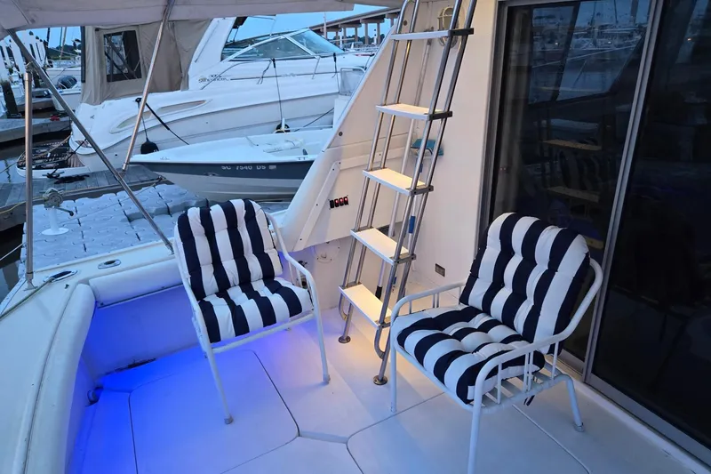 Slide: The Image of 1986 Silverton 34 Convertible Flybridge with striped chairs and ladder on deck. - 7