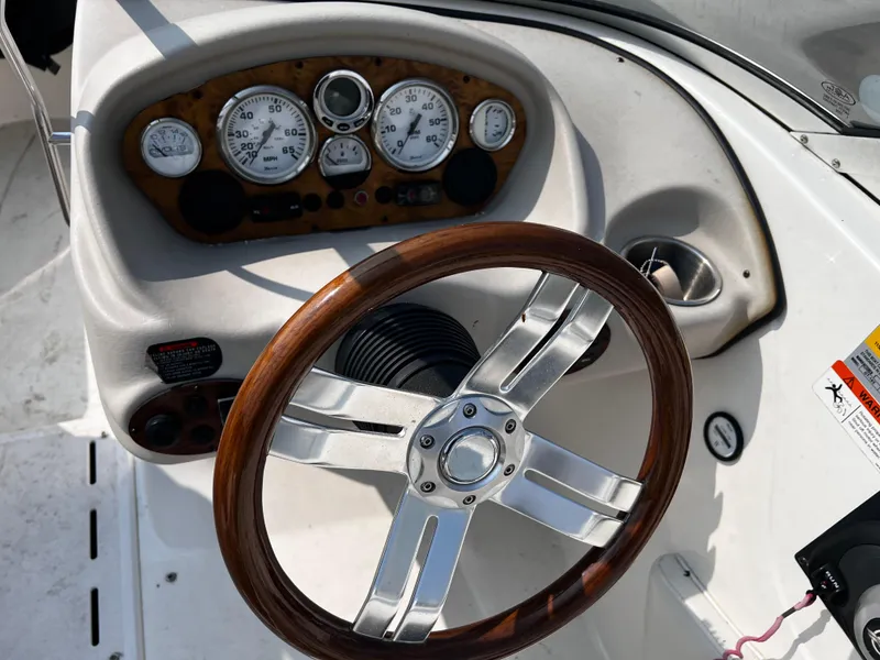 Slide: The Image of 2009 Glastron GT 185 boat dashboard with wood-accented steering wheel and gauges. - 8