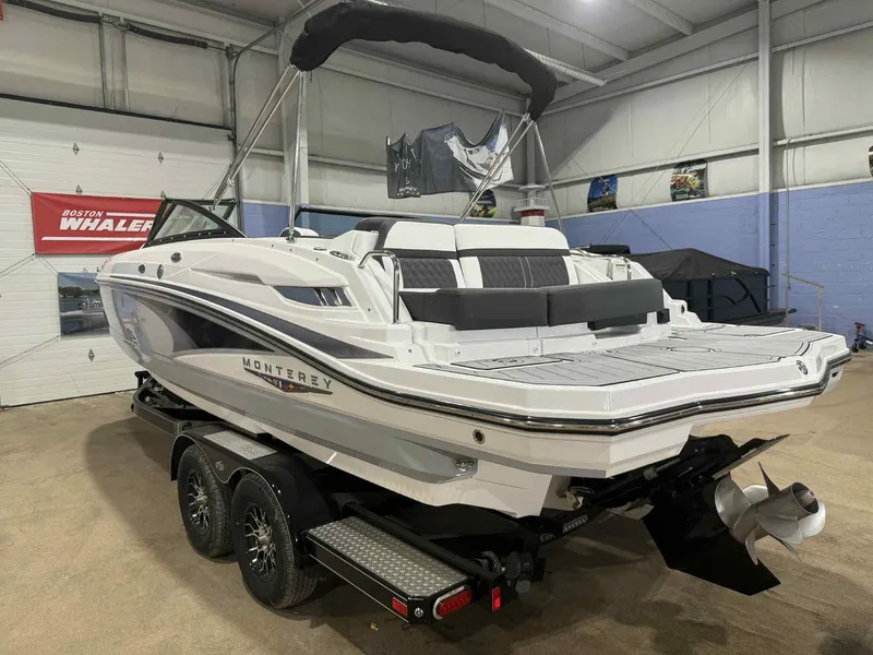 Slide: The Image of 2025 Monterey M4 boat in showroom, featuring sleek design and dual-axle trailer. - 2