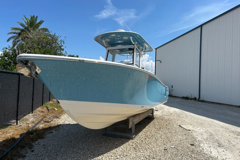 The Image of 2018 Sportsman 282 boat in storage, blue hull, sunny day, near warehouse. - 0